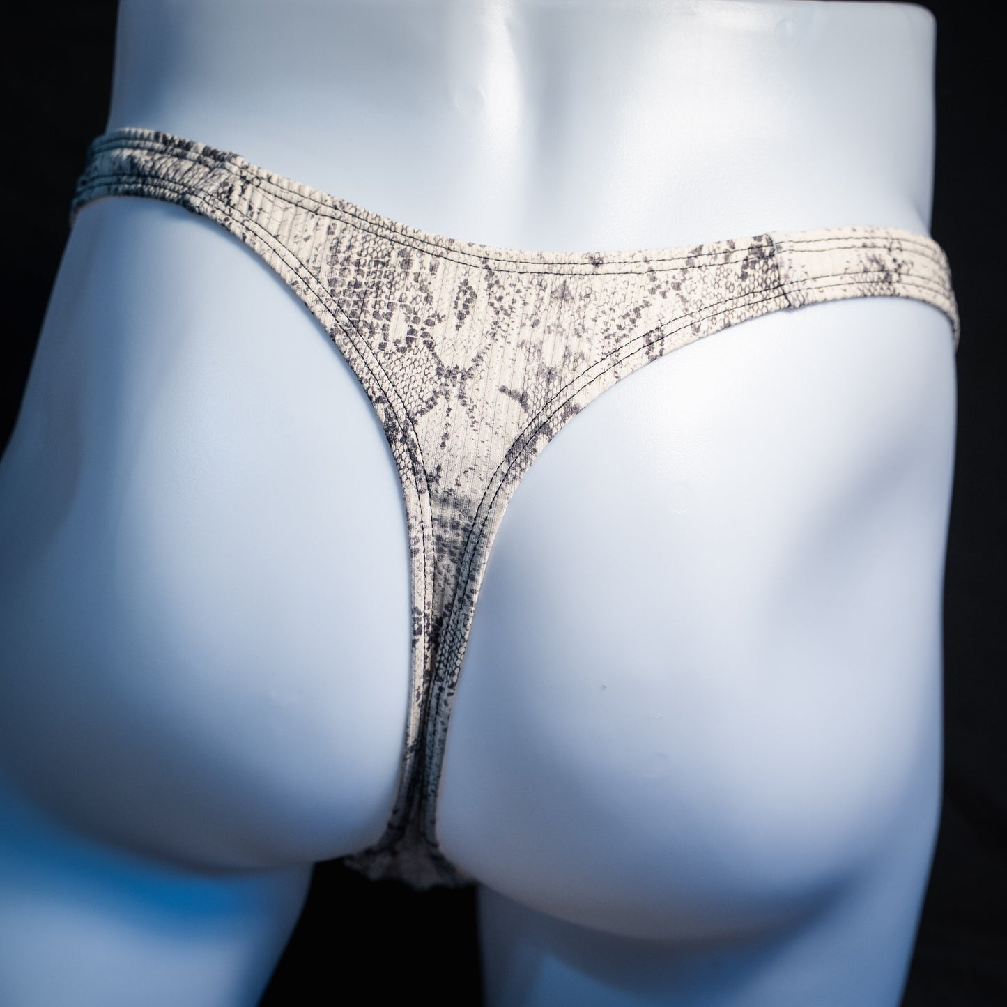 Men's beige snakeskin thong underwear, ribbed fabric, slim cut, rear view.