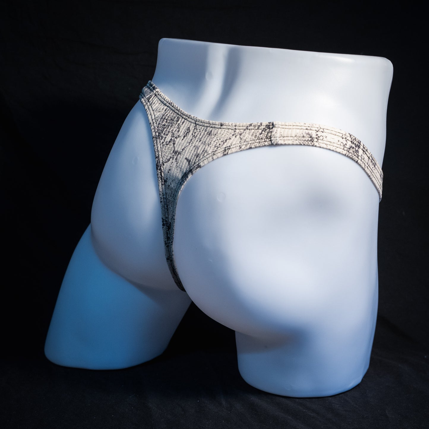 Men's beige snakeskin thong underwear, ribbed fabric, slim cut, rear view.