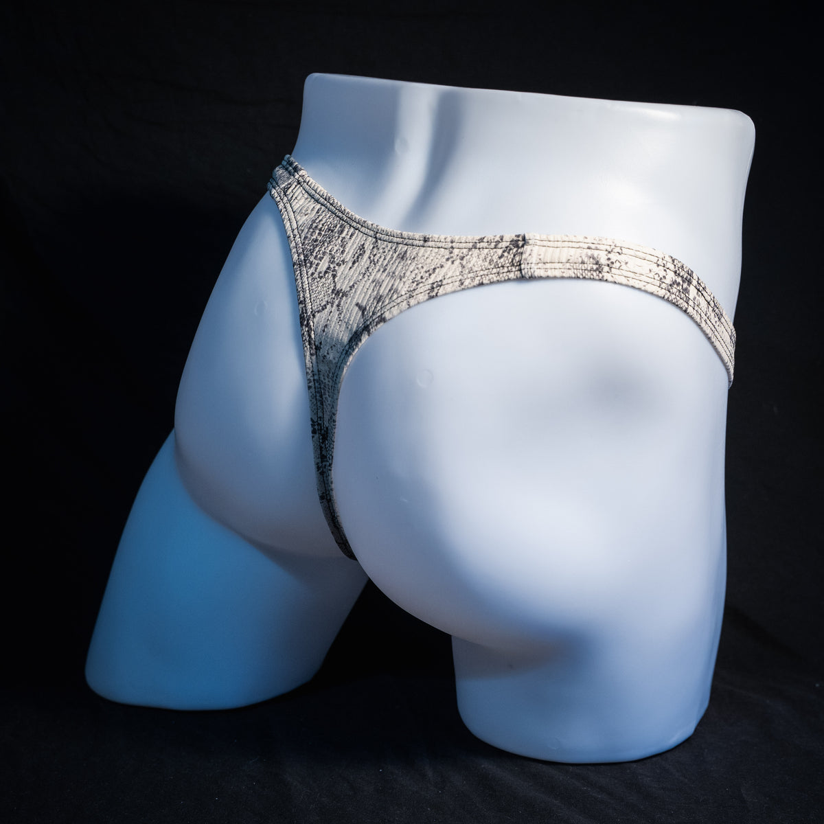 Men's beige snakeskin thong underwear, ribbed fabric, slim cut, rear view.