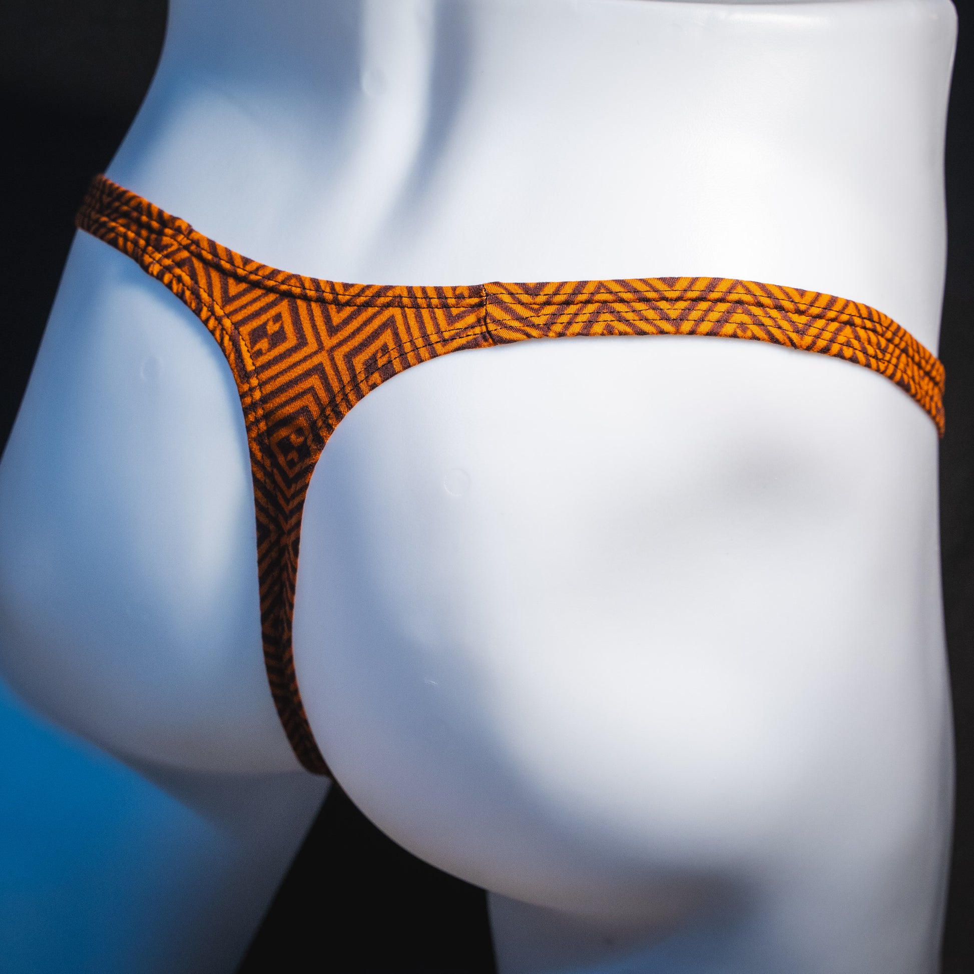 Men's geometric rust thong underwear, classic cut, angled rear view.
