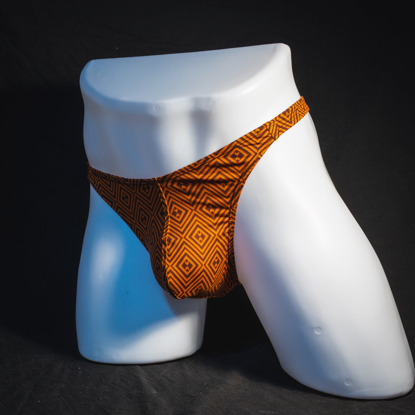 Men's geometric rust thong underwear, classic cut, angled full front view.