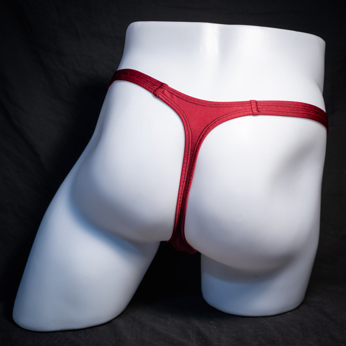 Men's solid maroon red thong underwear, classic cut, rear view.