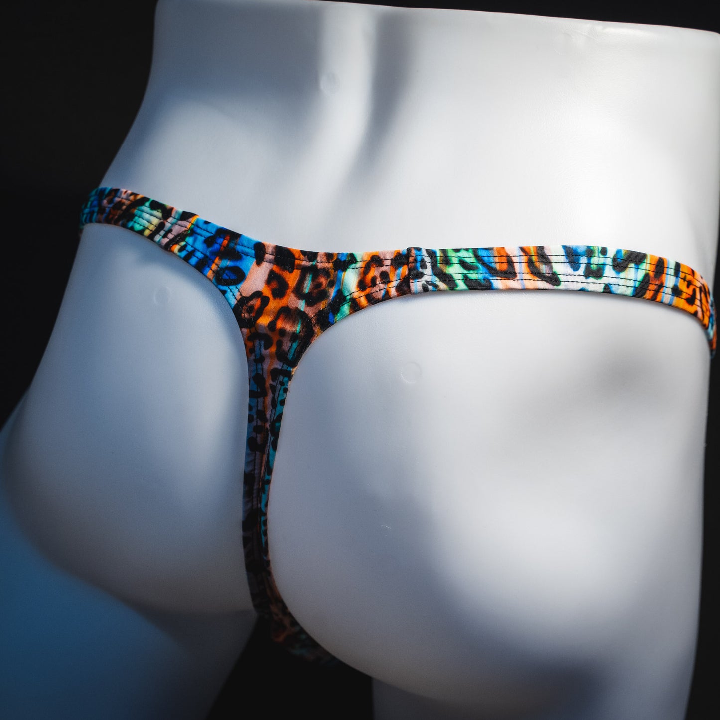 Men's colorful cheetah thong underwear, classic cut, rear angled view.