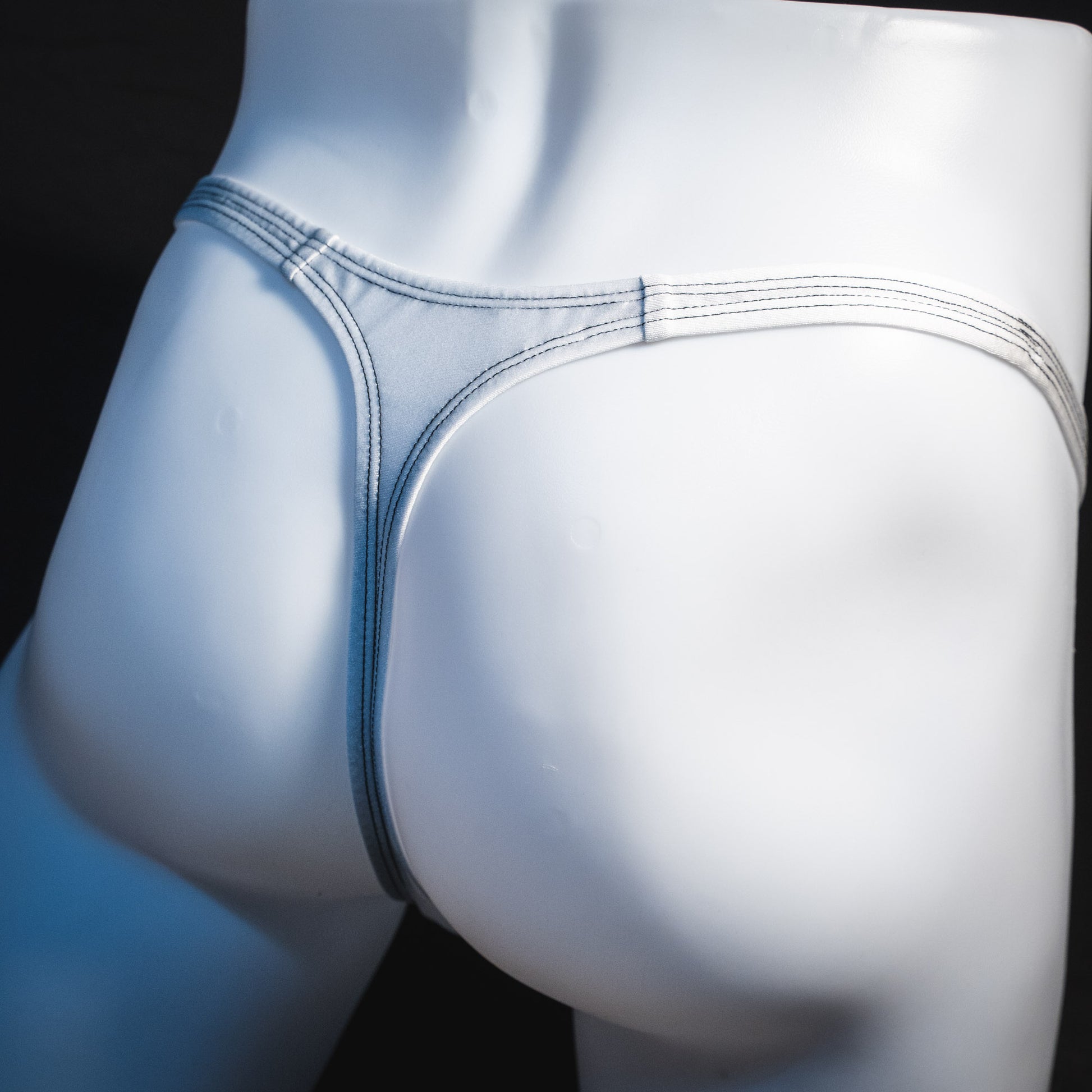 Men's white mesh thong underwear, classic cut, angled rear view.
