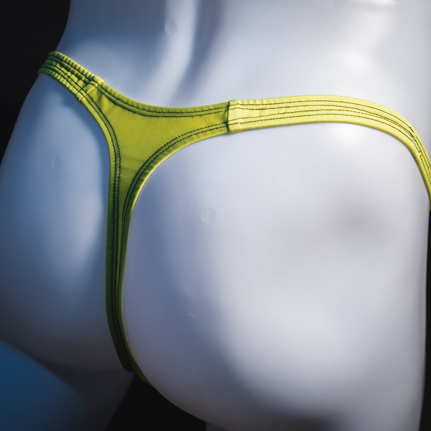 Men's yellow and black mesh thong underwear, classic cut, angled rear view.