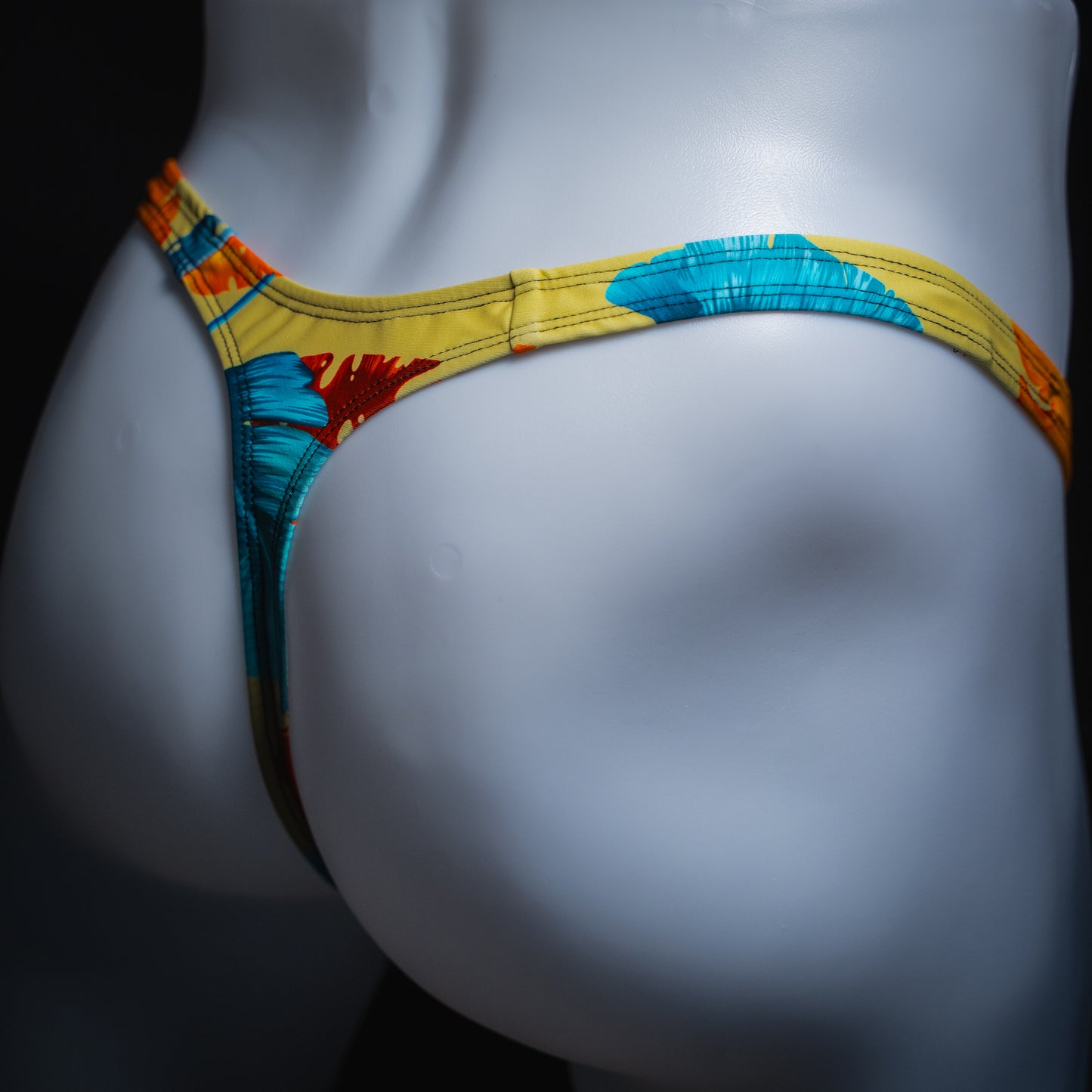 Men's yellow floral thong, slim cut, angled rear view.