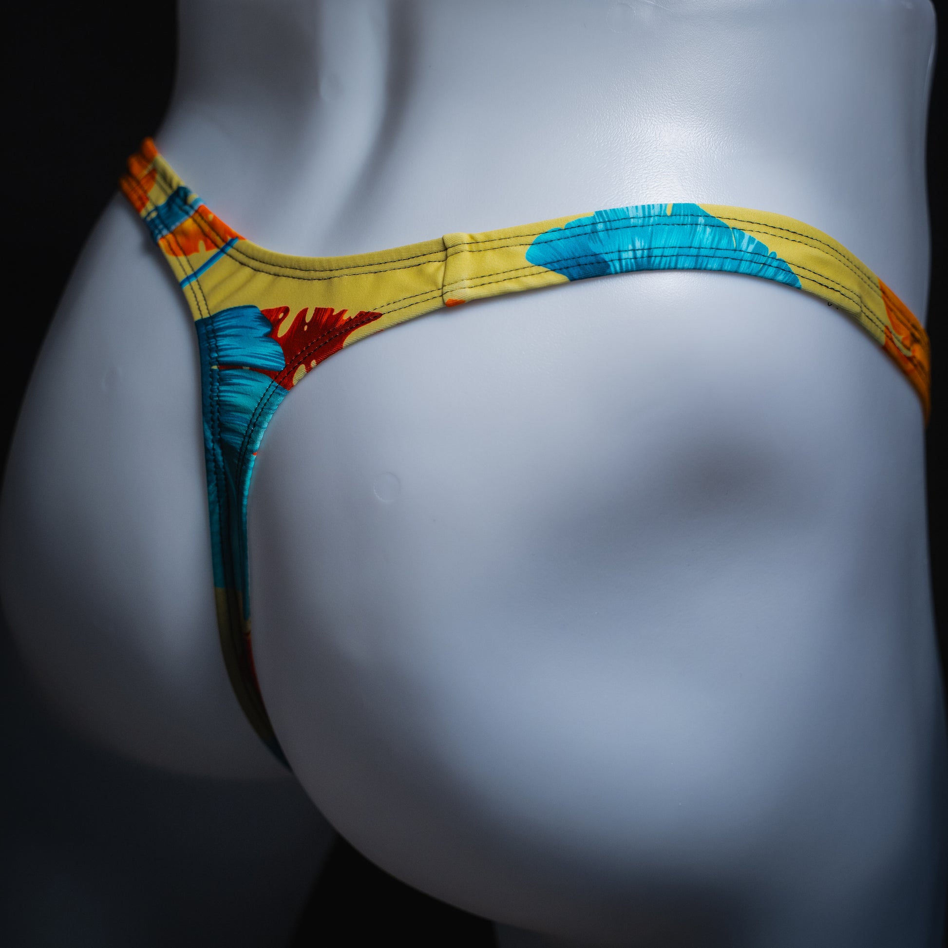 Men's yellow floral thong, slim cut, angled rear view.