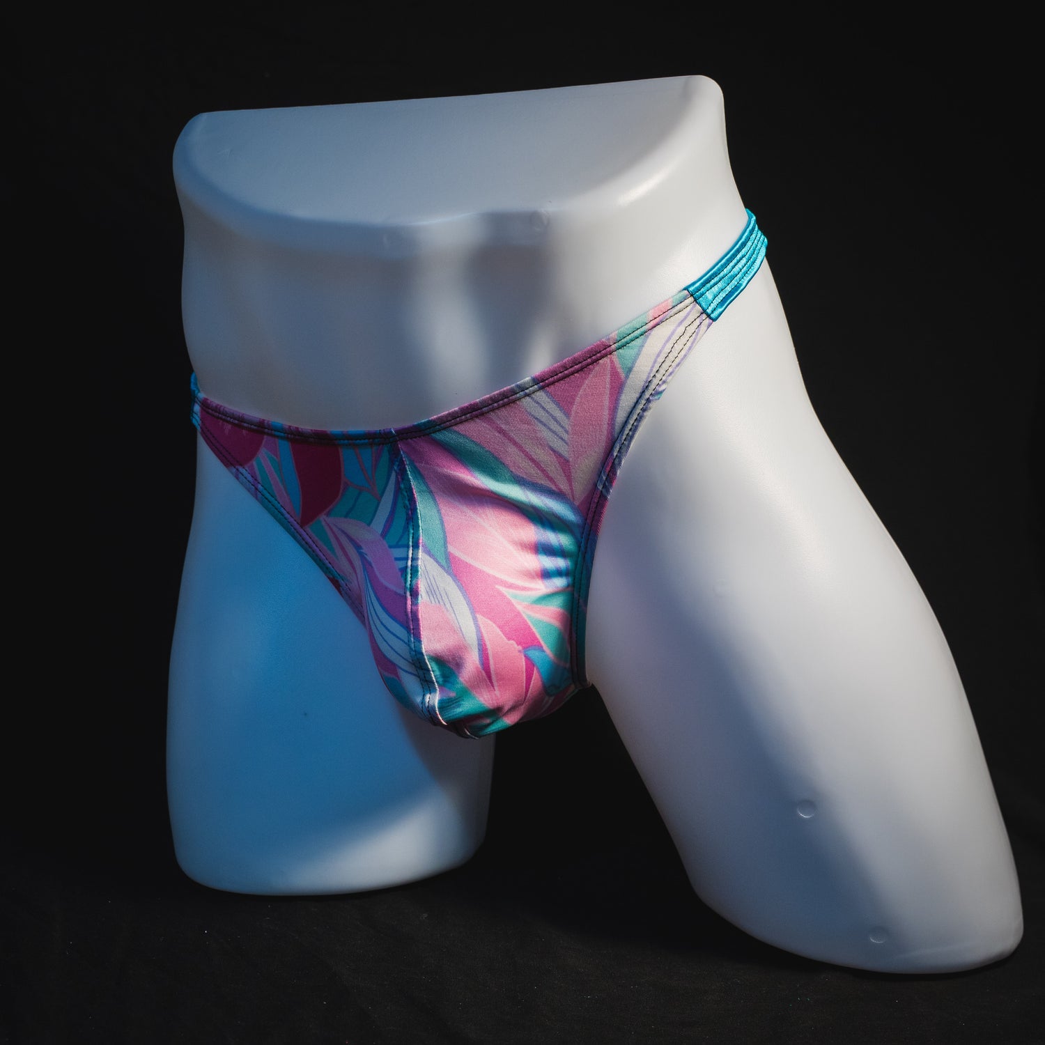Men's pink and blue feathers thong underwear, classic cut, angled full front view.