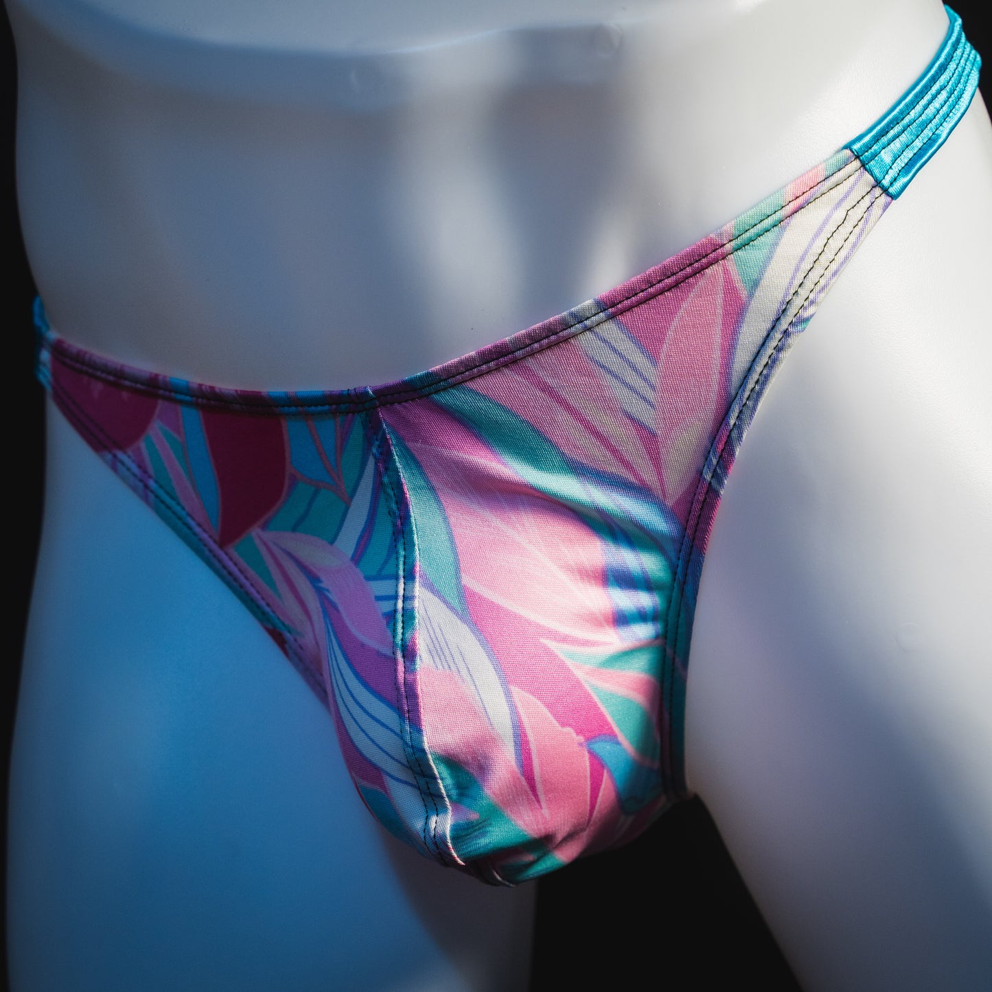 Men's pink and blue feathers thong underwear, classic cut, angled front view.