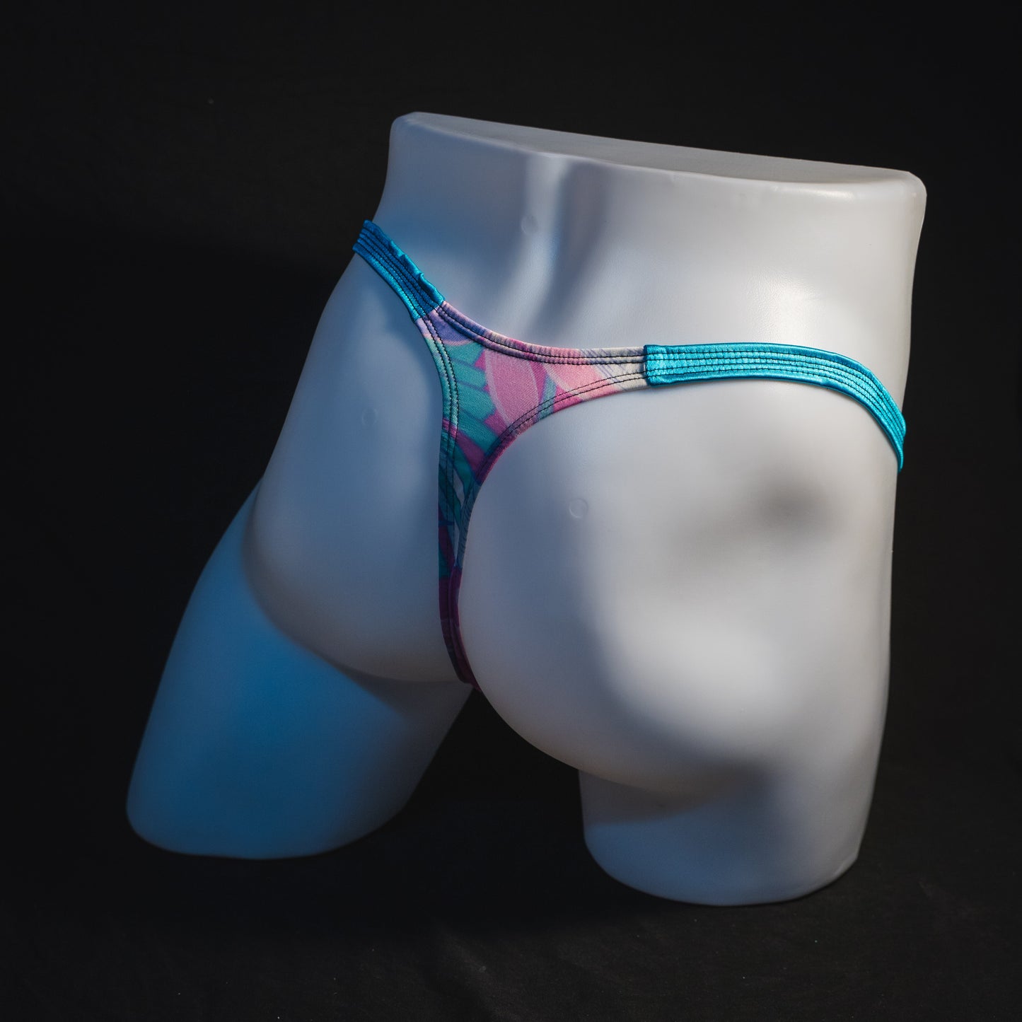 Men's pink and blue feathers thong underwear, classic cut, full angled rear view.