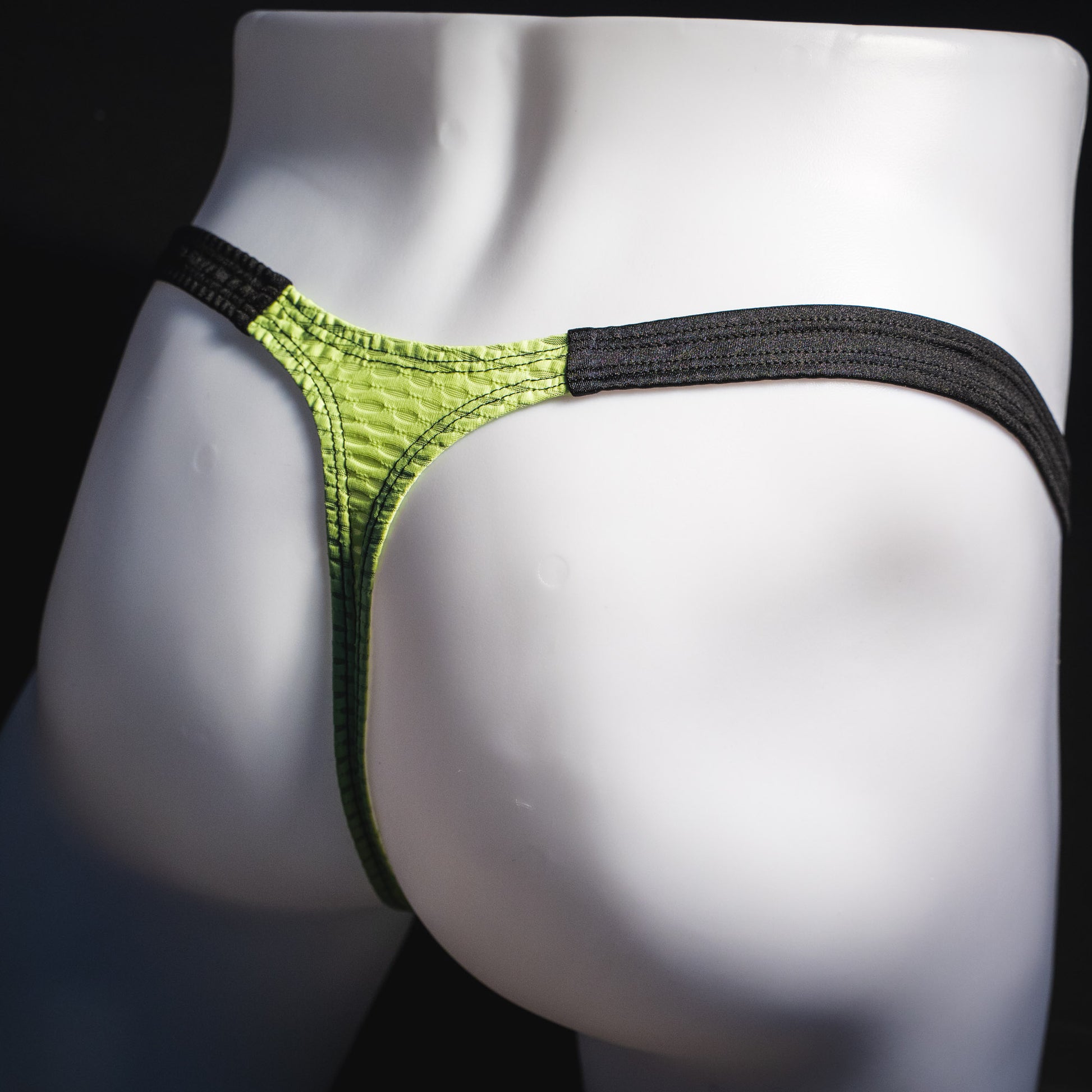 Men's lime green and black athletic mesh thong underwear, classic cut, angled rear view.