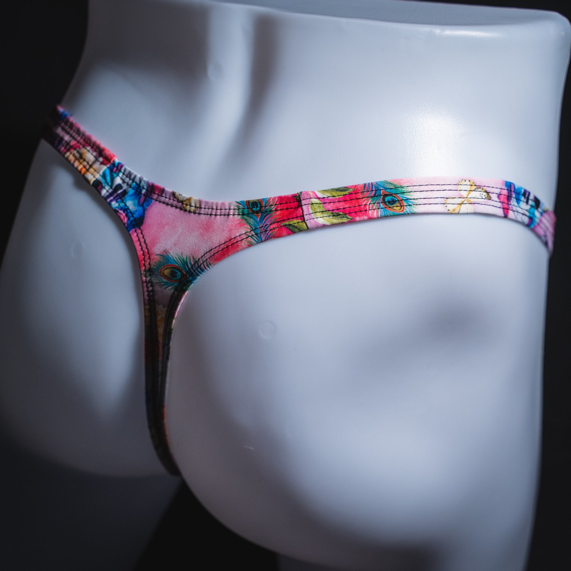 Men's pink skulls and floral thong underwear, classic cut, angled rear view.