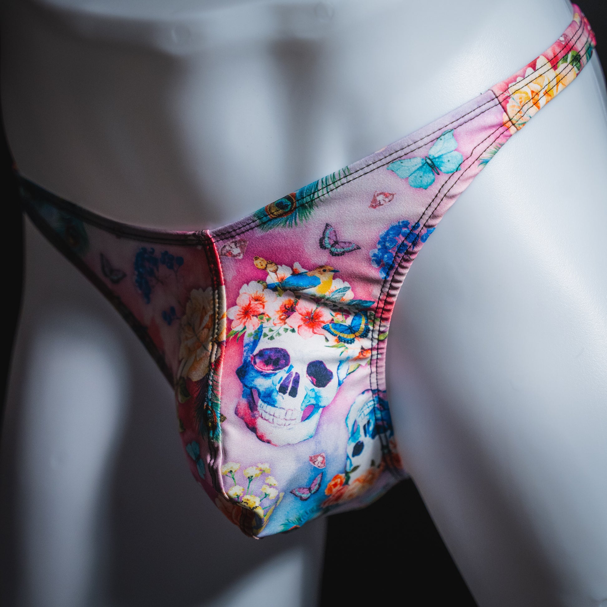 Men's pink skulls and floral thong underwear, classic cut, angled front view.