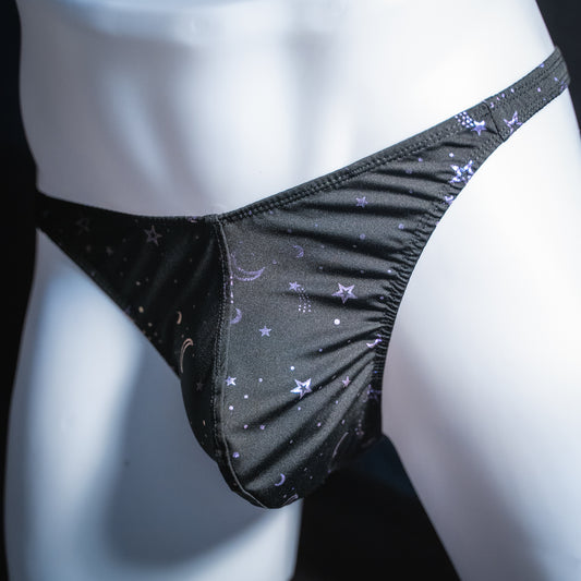 Men's black with purple foil moons and stars thong, classic cut, angled front view.