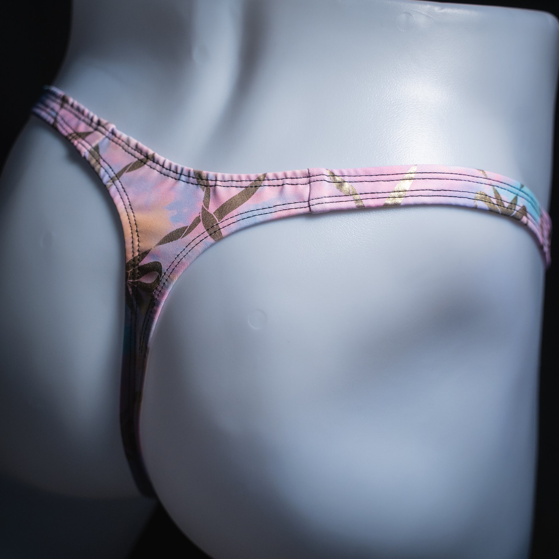 Men's pink and purple with gold foil chains thong, slim cut, angled rear view.
