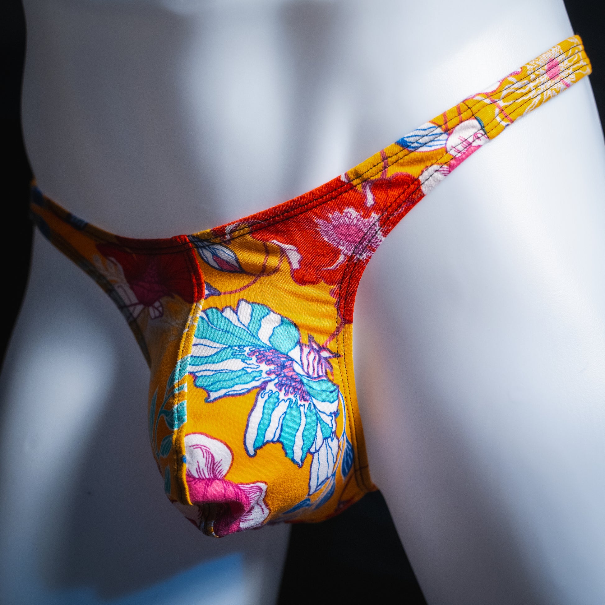Men's vintage orange floral thong, slim cut, angled front view.