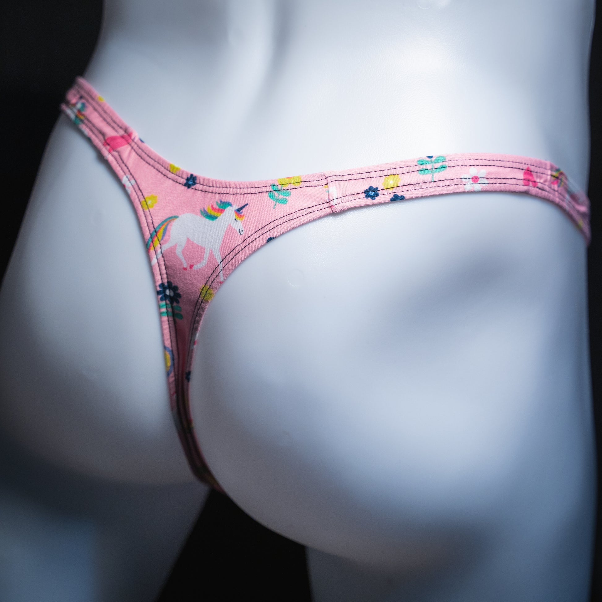 Men's pink unicorn thong, slim cut, angled rear view.