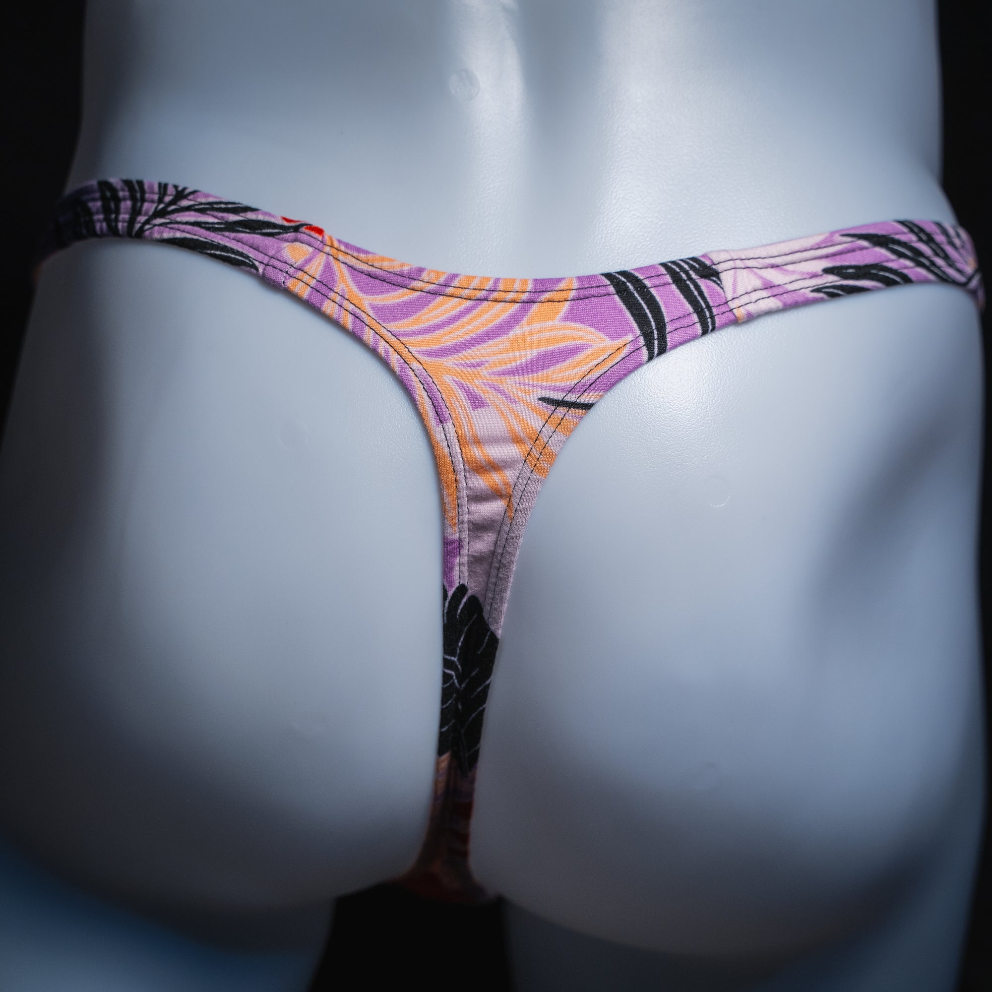 Men's vintage purple Hawaiian floral thong, slim cut, rear view.