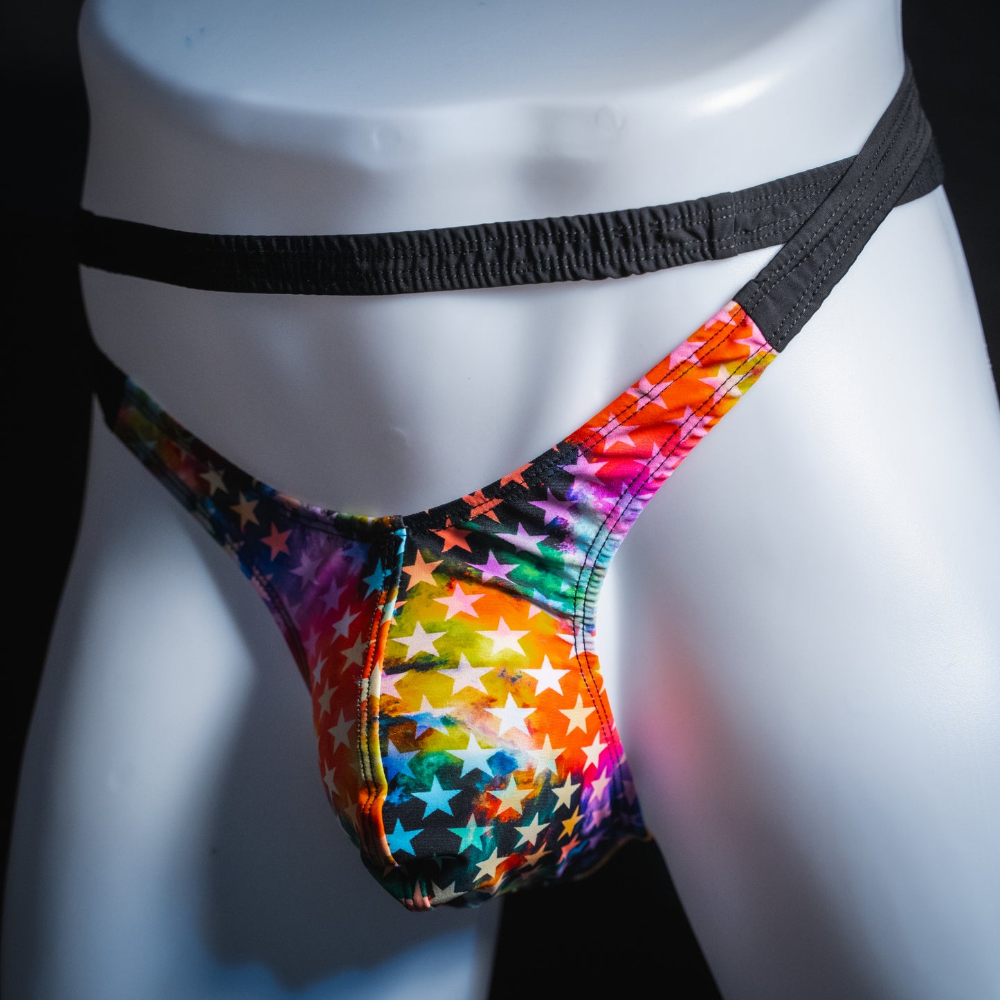 Men's double strap thong with star pattern, slim cut, angled front view.