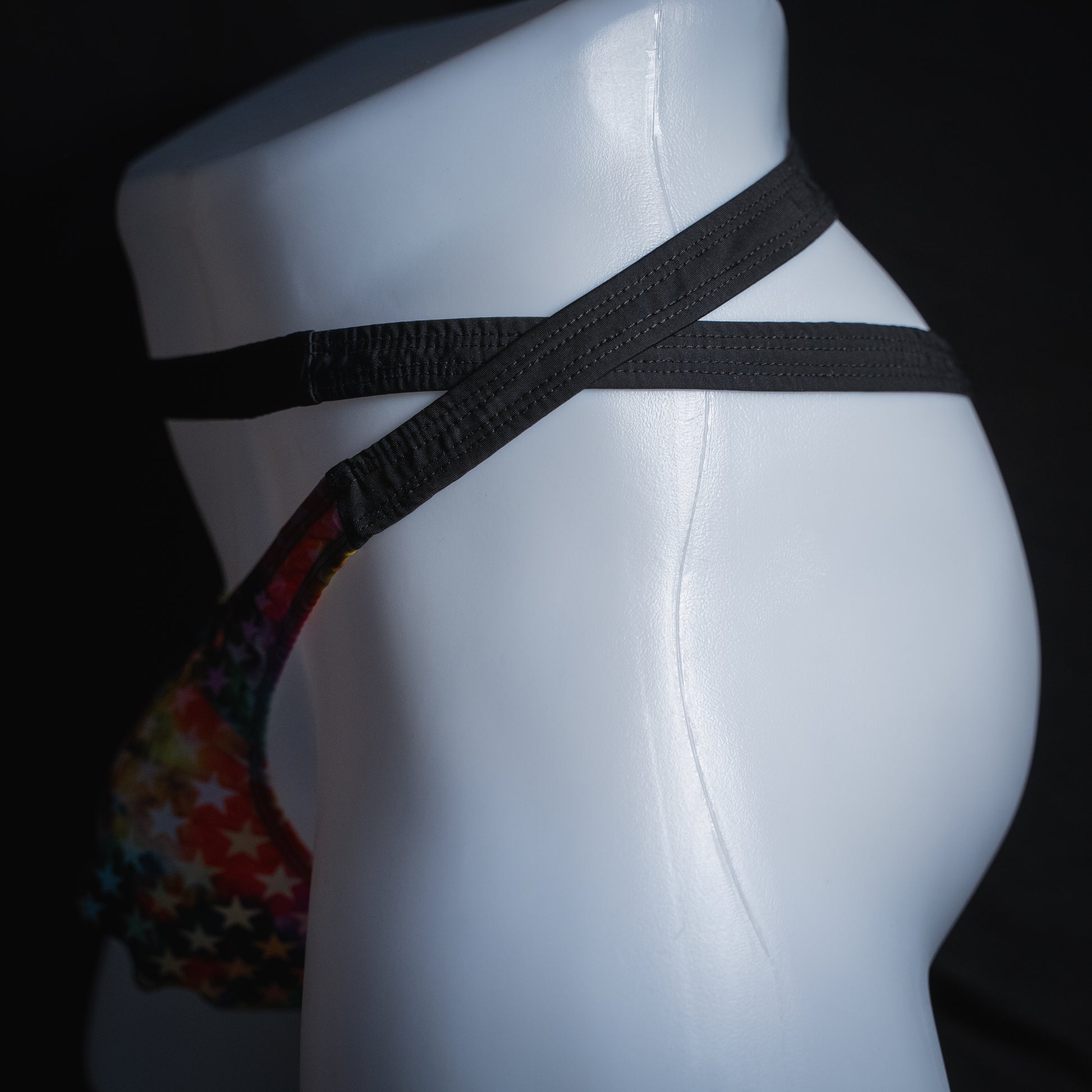 Men's double strap thong with star pattern, slim cut, side view.