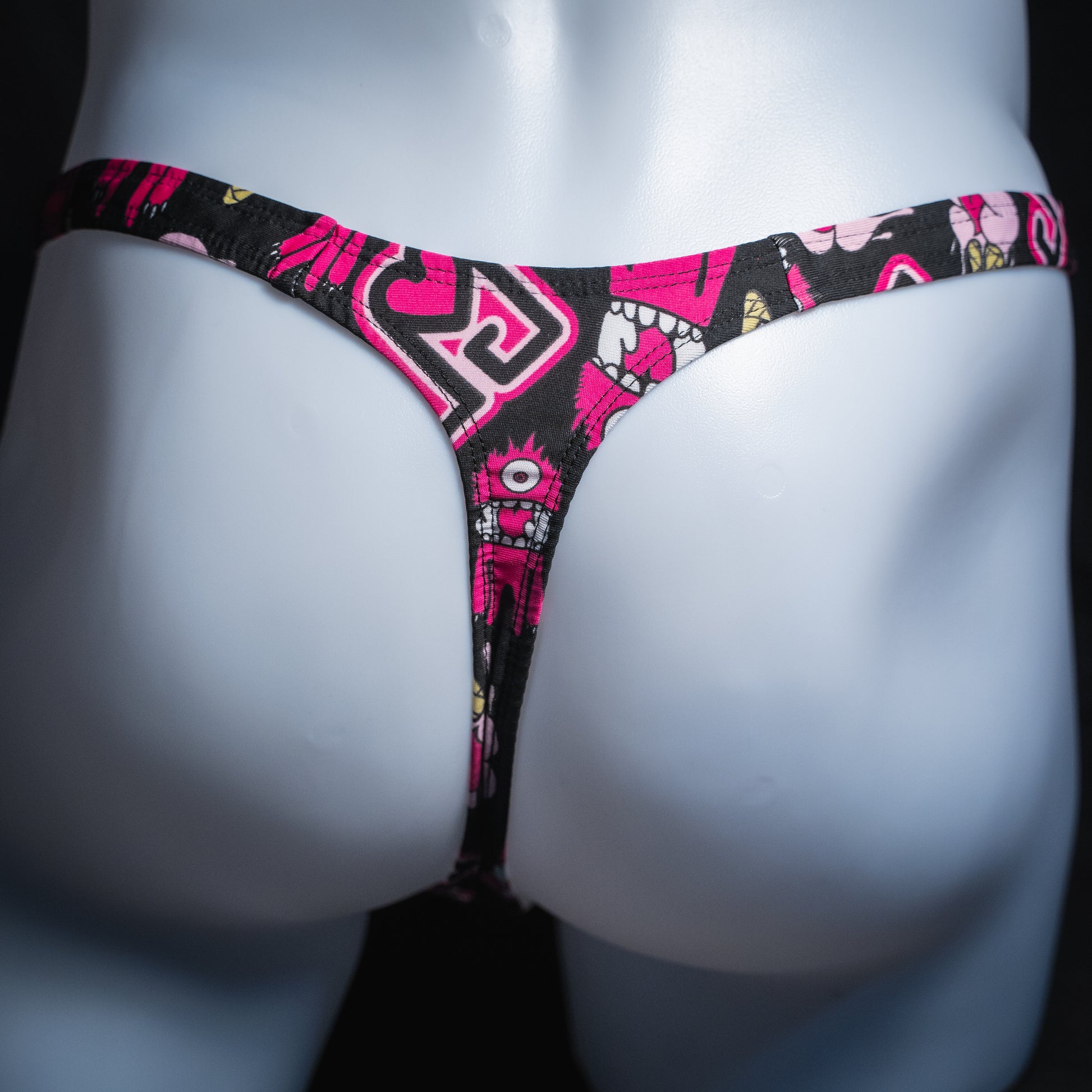 Men's pink monsters on black thong, slim cut, rear view.