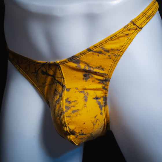Men's yellow and black tie dye thong, classic cut, angled front view.