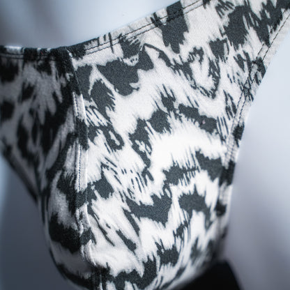 Men's black and white abstract cheetah thong, classic cut, closeup front view.