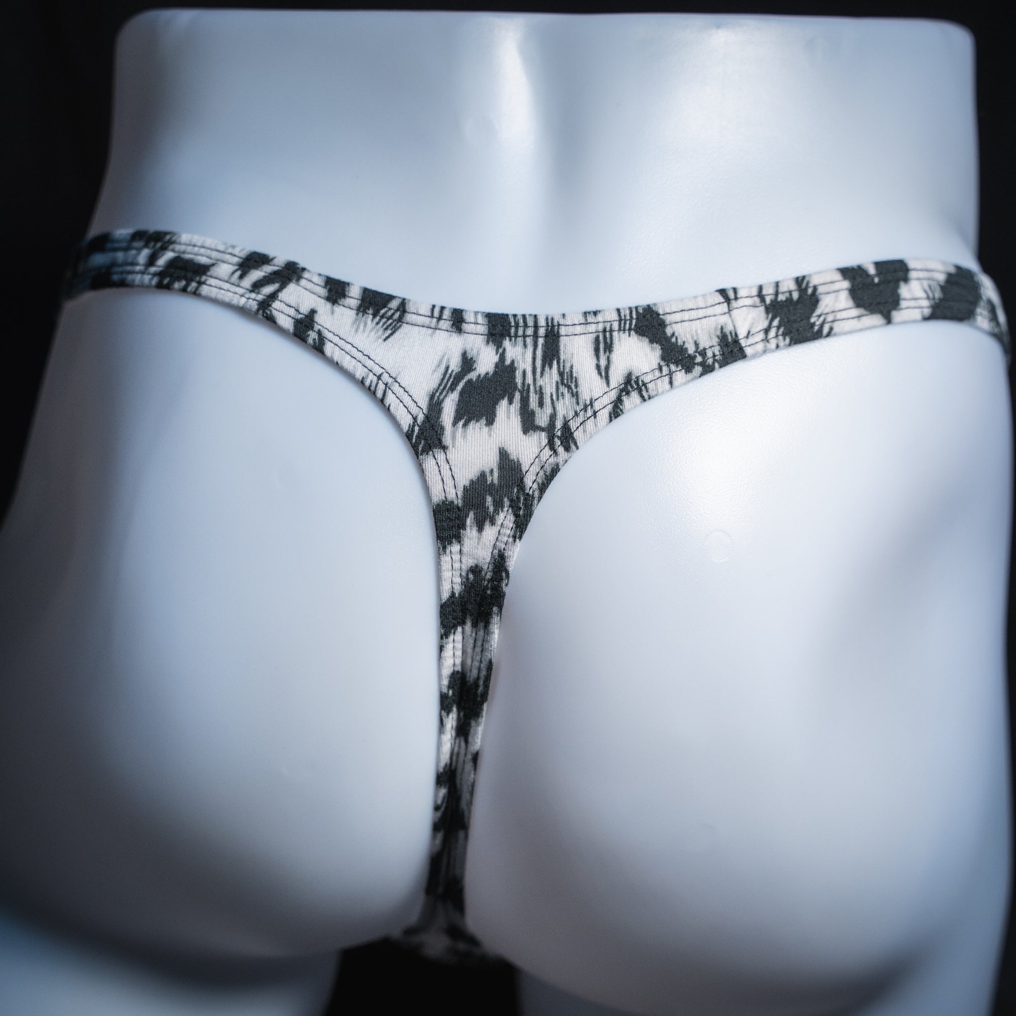 Men's black and white abstract cheetah thong, classic cut, rear view.
