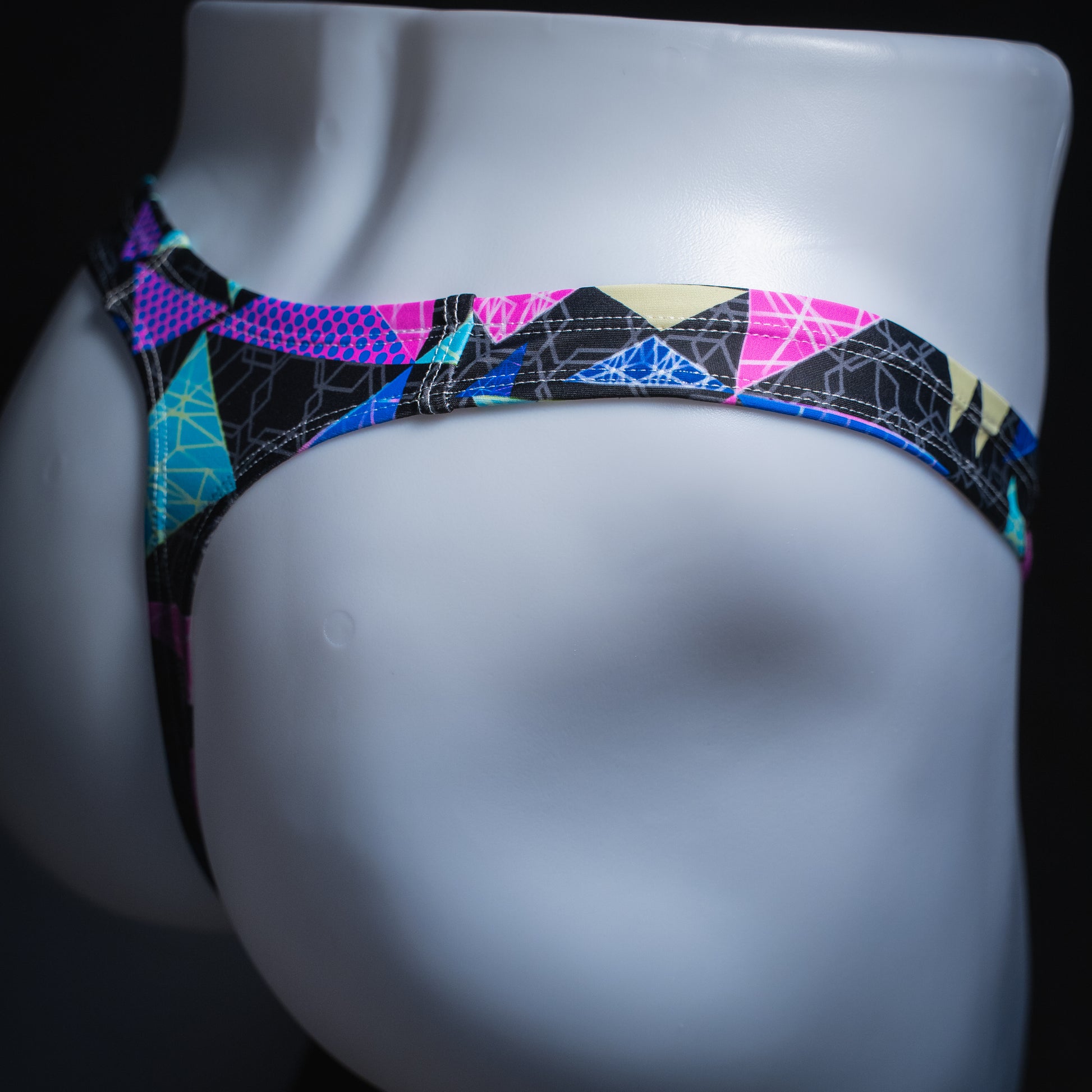 handmade mens thong underwear, bright geometric shapes pattern, robust cut design, spandex material, angled back view