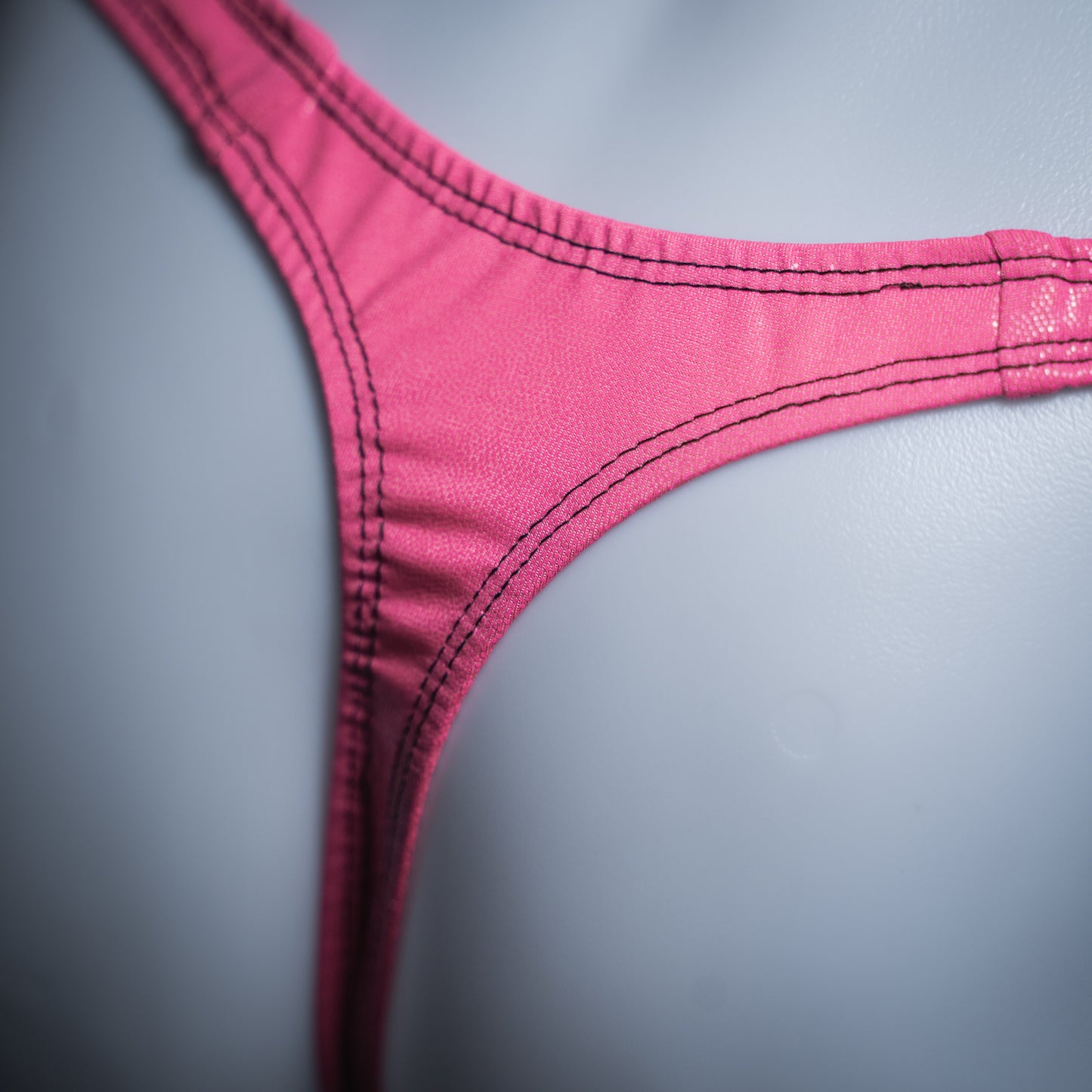 Men's bright pink metallic thong, slim cut, rear closeup view.