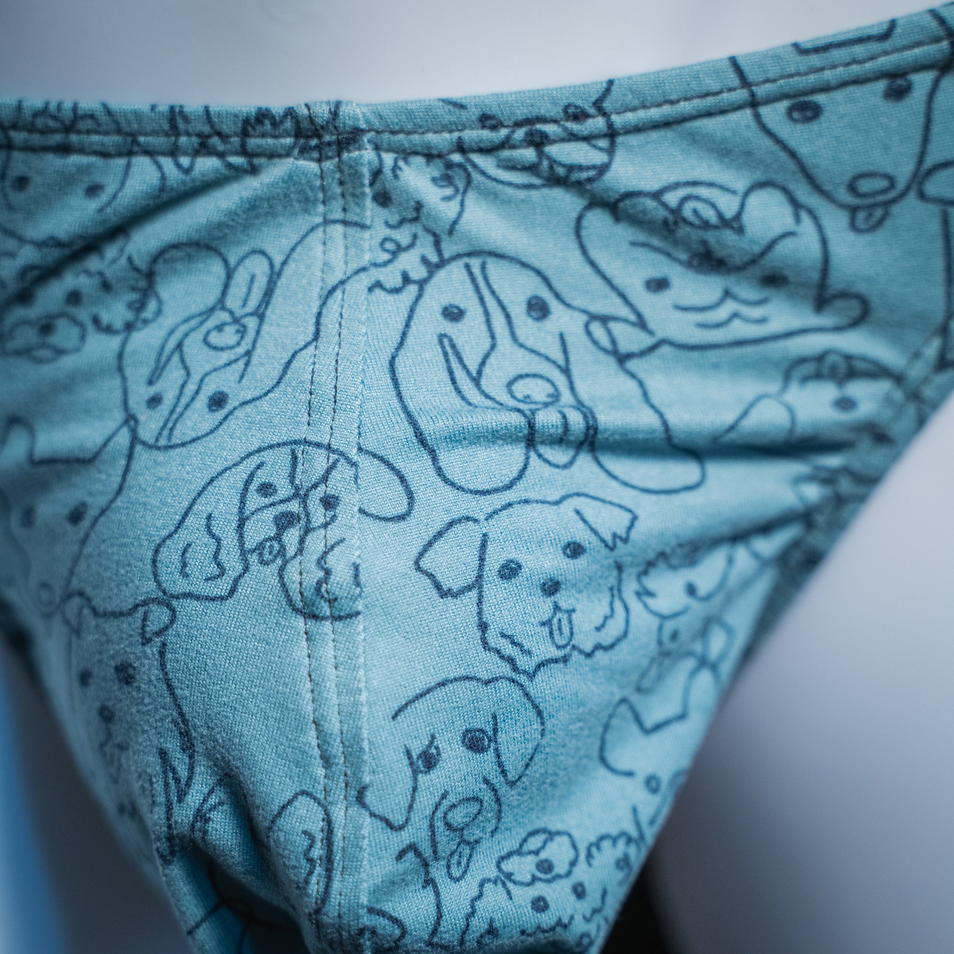 Men's dog faces on blue thong, classic cut, closeup front view.