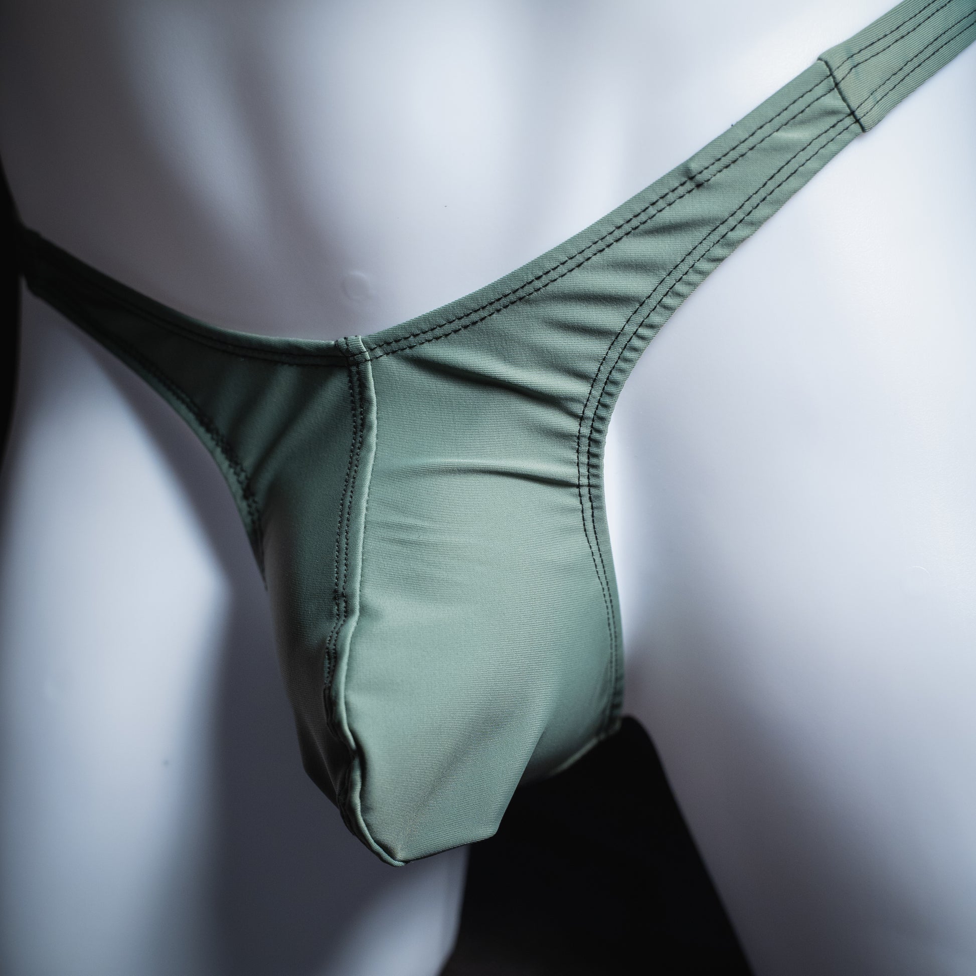 handmade mens thong underwear, muted green print, spandex material, slim cut, angled front view