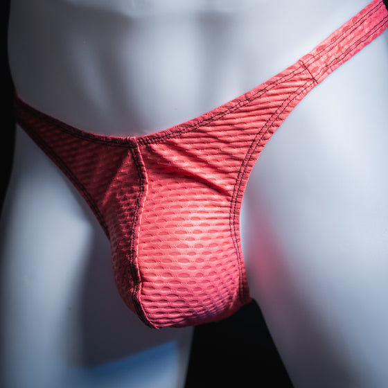 Men's pink yoga mesh thong, slim cut, angled front view.