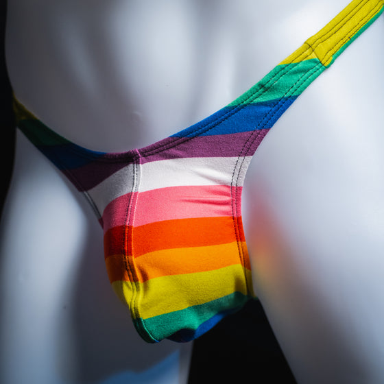 Men's rainbow striped thong underwear, slim cut, angled front view.