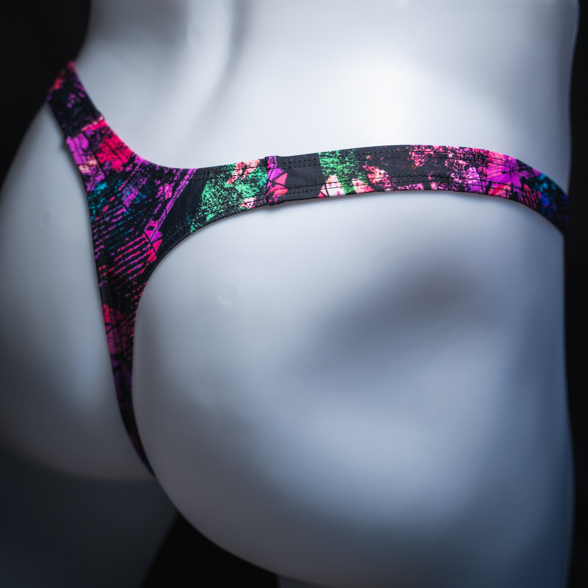 Men's pink and black abstract thong, slim cut, angled rear view.