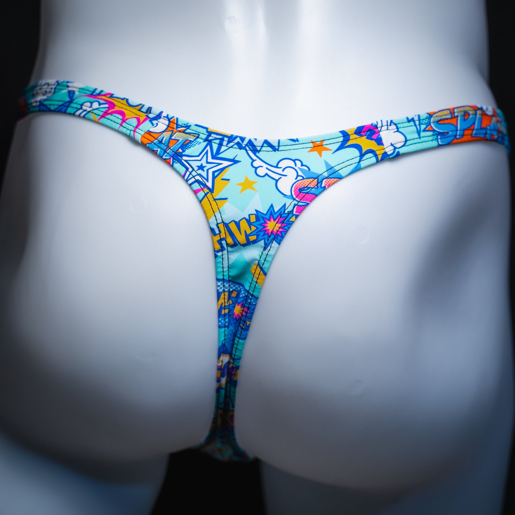 Men's blue thong with multicolored comic book words, slim cut, rear view.