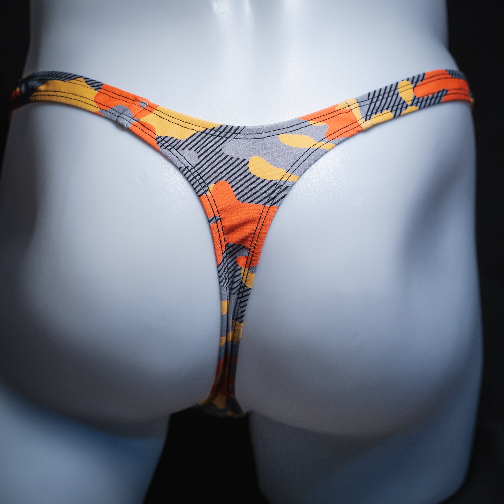 Men's orange and gray camo thong, slim cut, rear view.