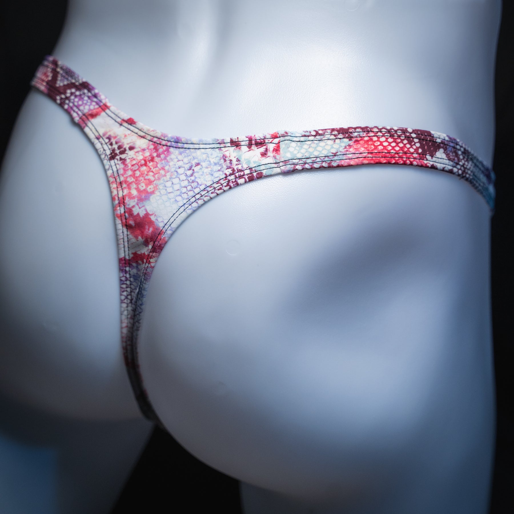 Men's pink snakeskin thong, slim cut, angled rear view.
