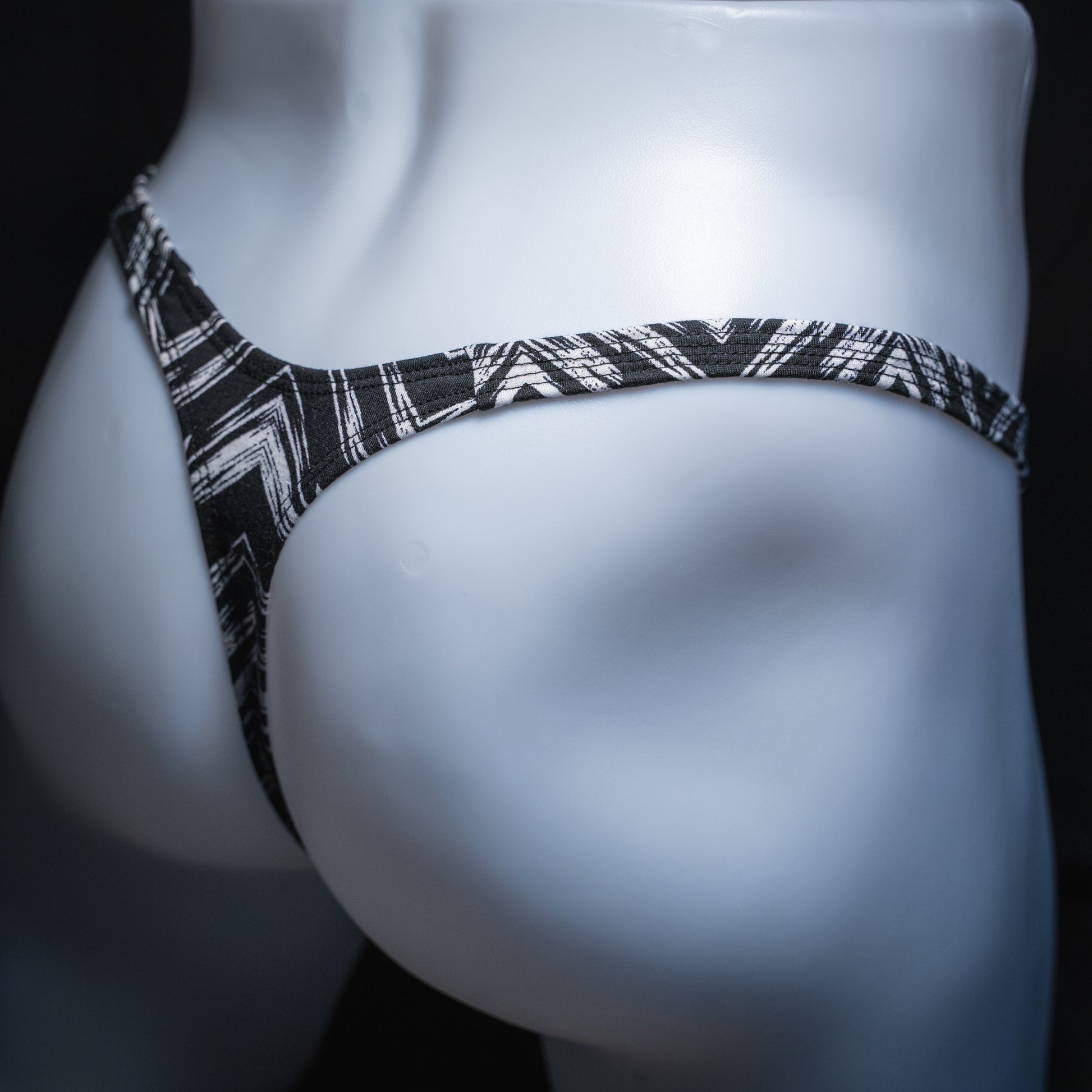 Mens' black and white zig zag striped thong, slim cut, angled rear view.