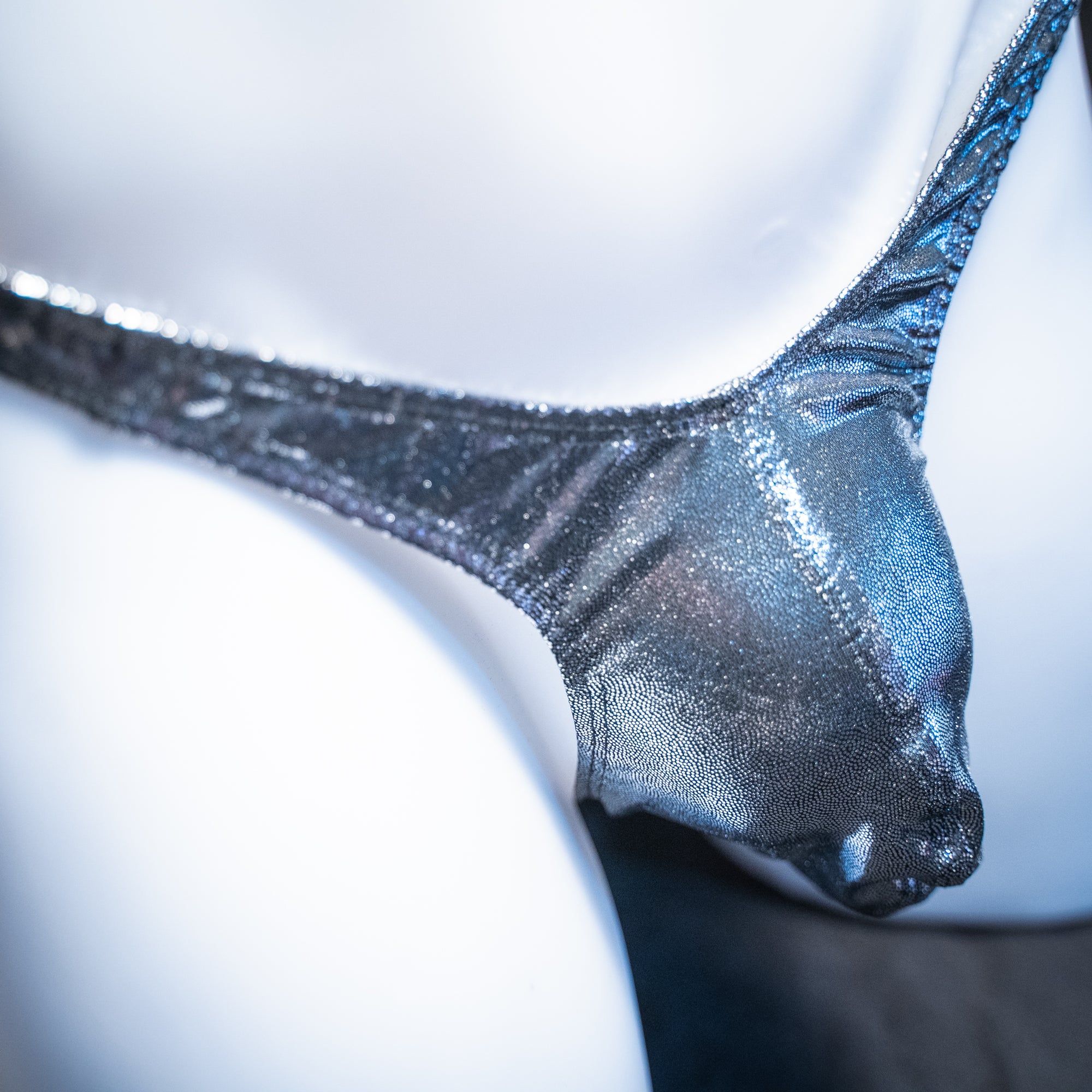 Men's metallic dark silver thong, slim cut, closeup angled front view.