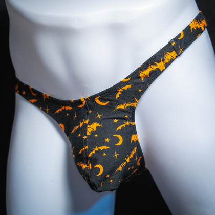 Men's thong underwear, halloween black and orange bats and moons print, polyester, handmade, slim cut, angled front view