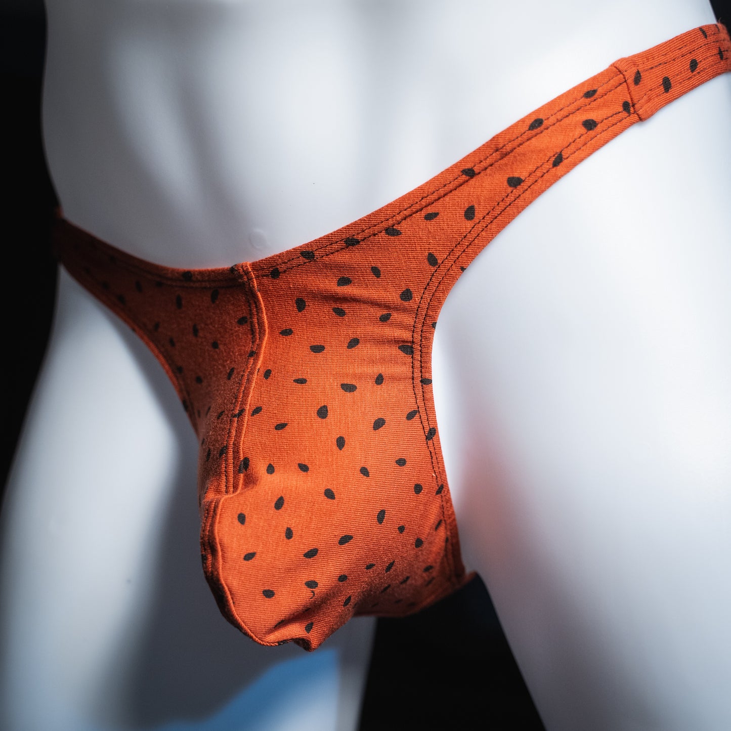Men's red watermelon seeds thong, slim cut, angled front view.