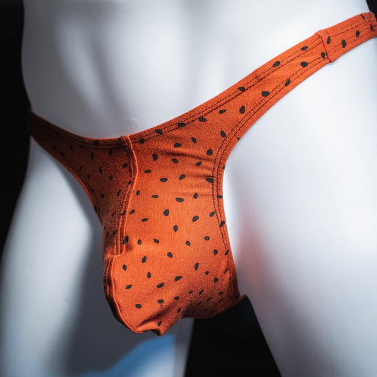 Men's red watermelon seeds thong, slim cut, angled front view.