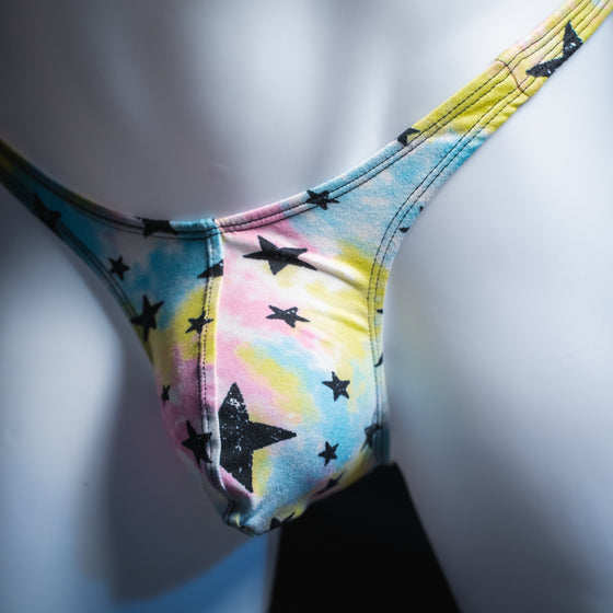 Men's tie dye with black stars thong, slim cut, angled front view.