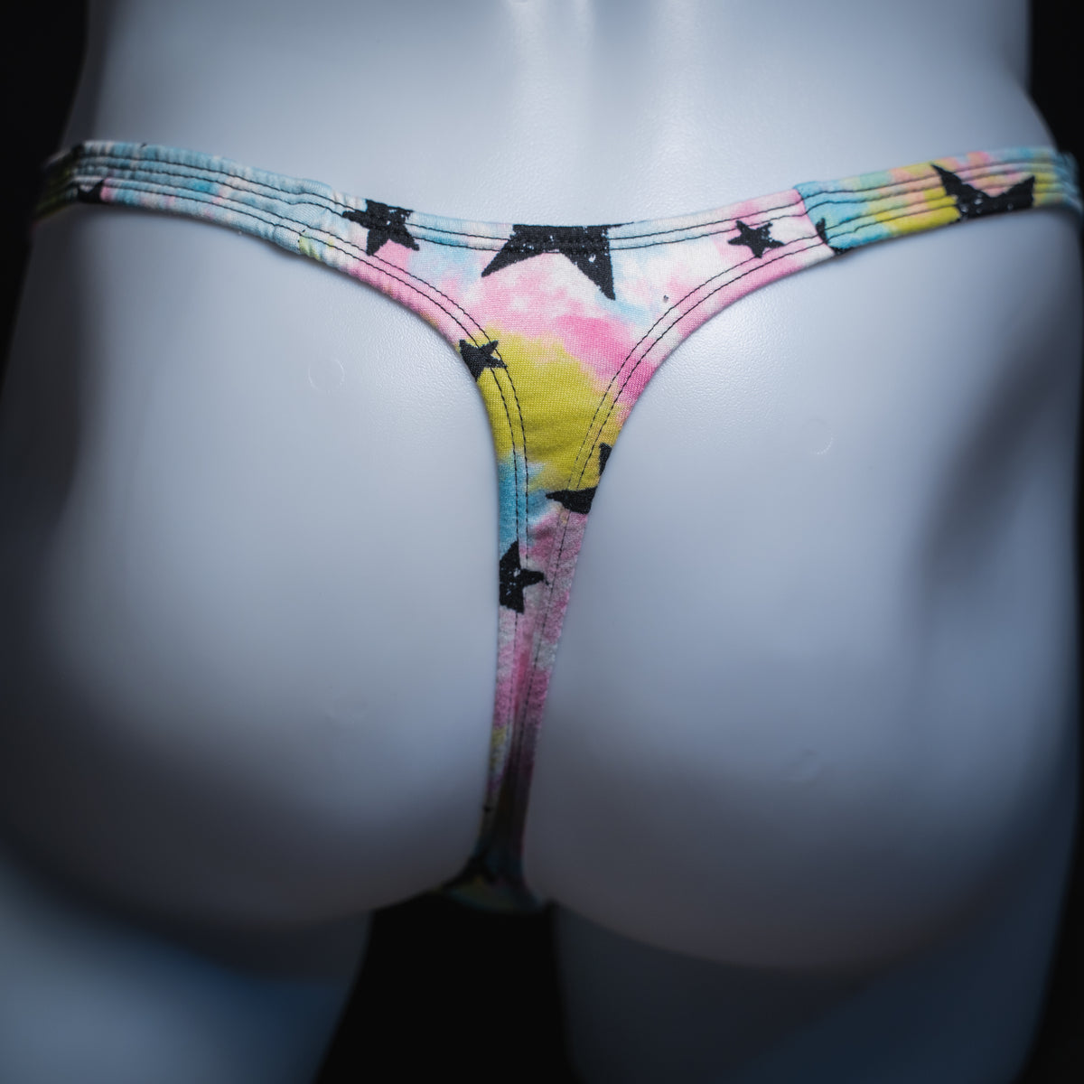 Men's tie dye with black stars thong, slim cut, rear view.